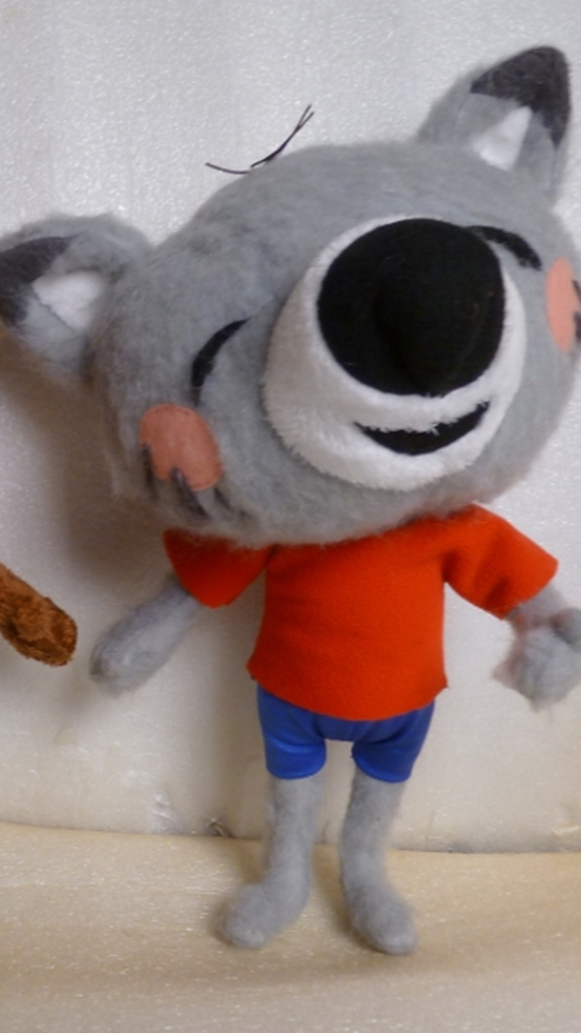 Grey cartoon cat plush with a closed-eye grin, white muzzle, red-orange T-shirt and blue shorts, made to order