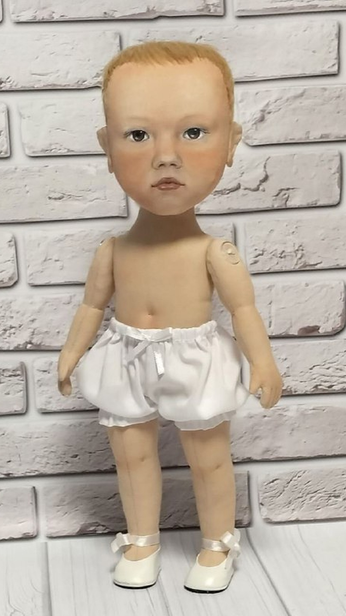Cloth body of a custom baby doll in white bloomers and ribbon shoes, painted face, sewn to order from a photo
