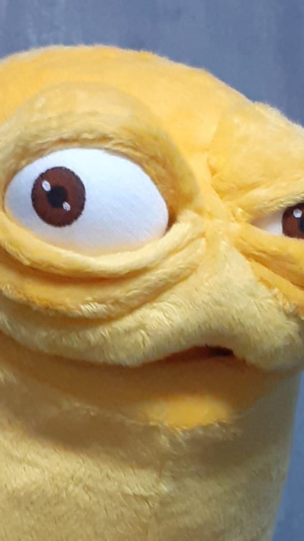 Hand-sculpted wrinkles and a round brown-and-white eye on a custom yellow monster mascot plush, made to order