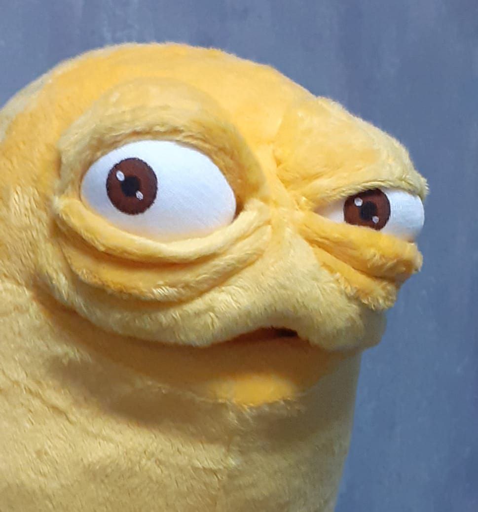 Monster mascot plush face Hand-sculpted wrinkles and round brown-and-white eyes on a custom yellow monster mascot plush, made to order