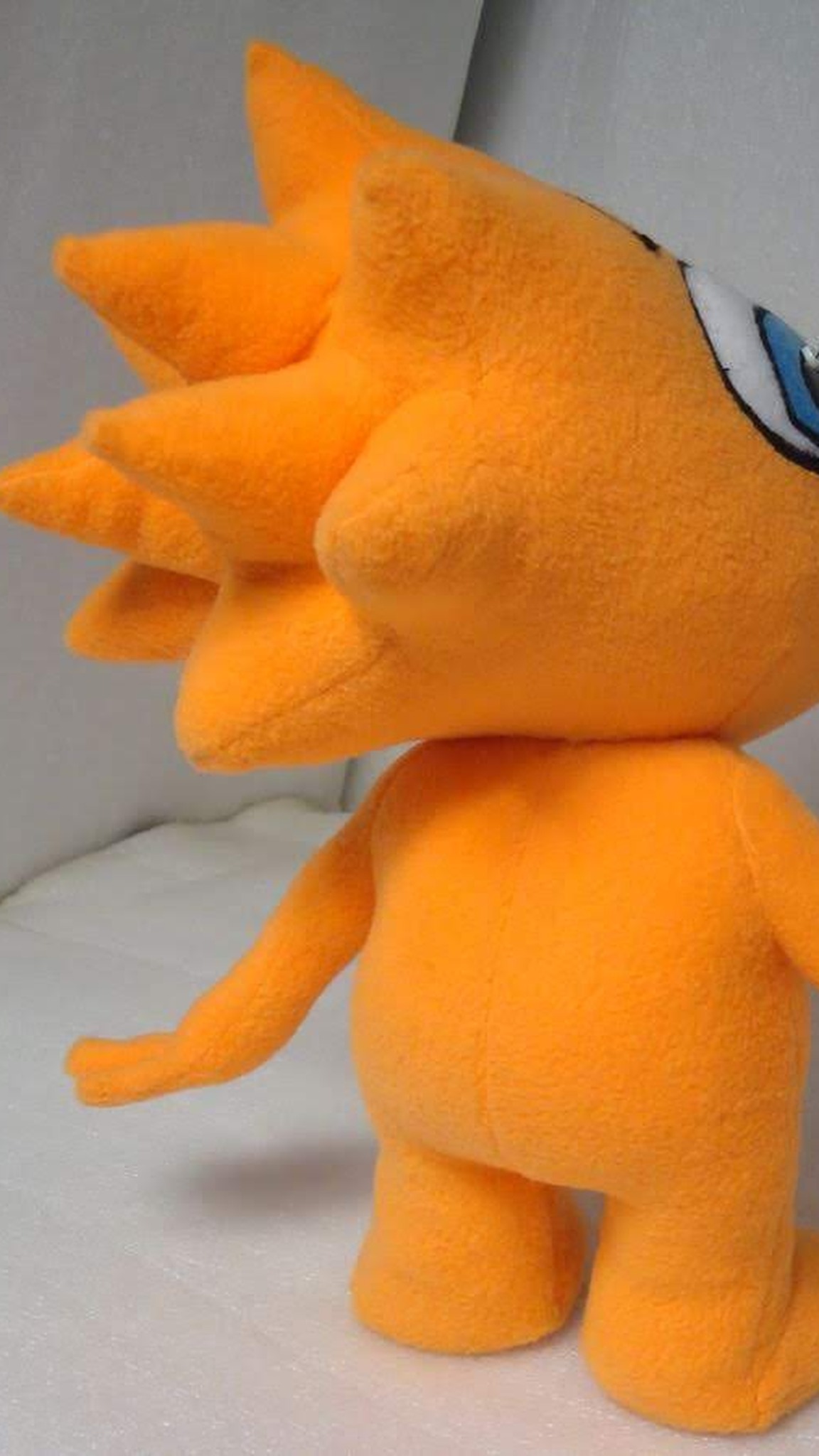 Cartoon mascot plush from behind: nine orange cone spikes of hair on the custom plush head, made to order