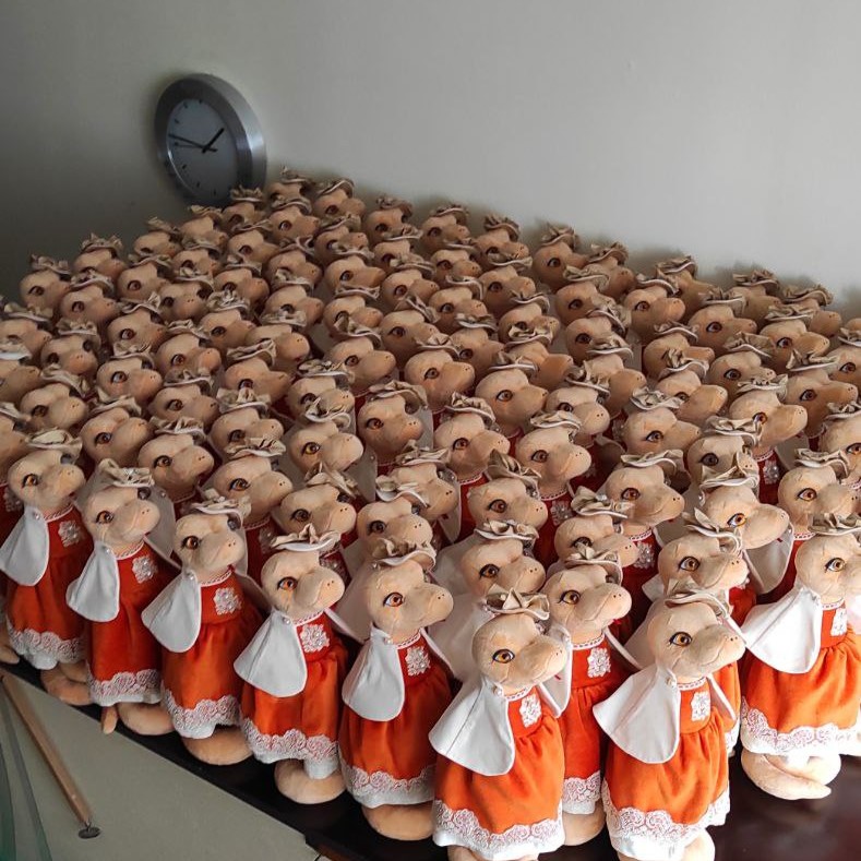 Corporate plush toys batch: snake ladies A full table of snake plush ladies in orange dresses, a corporate plush toys batch sewn by hand to order