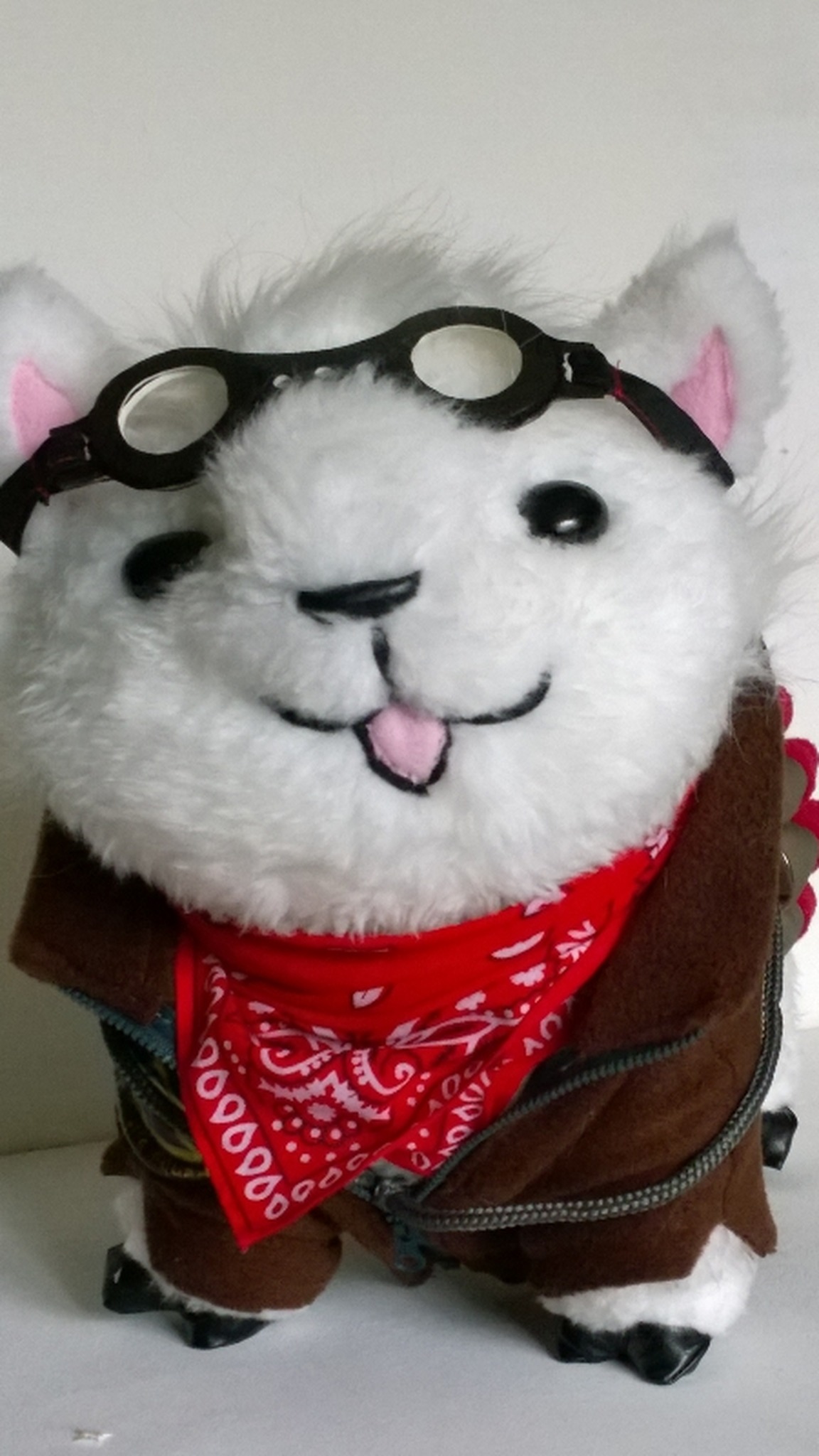 Custom alpaca plush with a winking face and pink tongue, goggles and a red bandana, handmade to order
