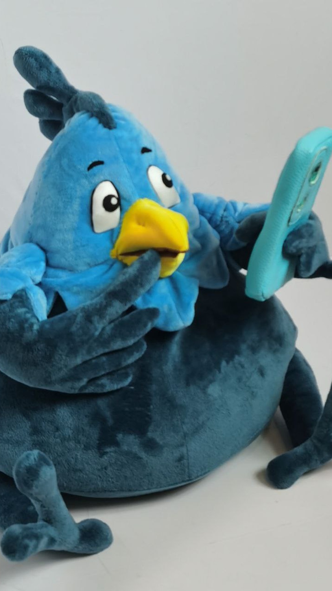 Custom bird plush with a wing to its beak and a phone in the other, dark teal mottled plush, made to order
