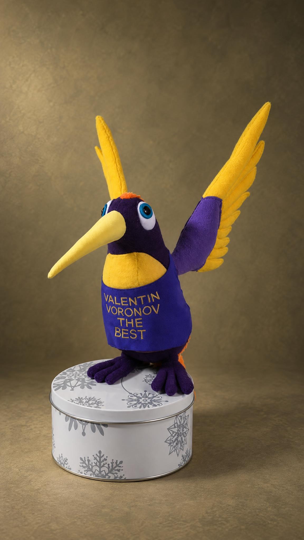 Purple bird plush with yellow feather wings and a gold-lettered name vest, sewn by hand as a gift