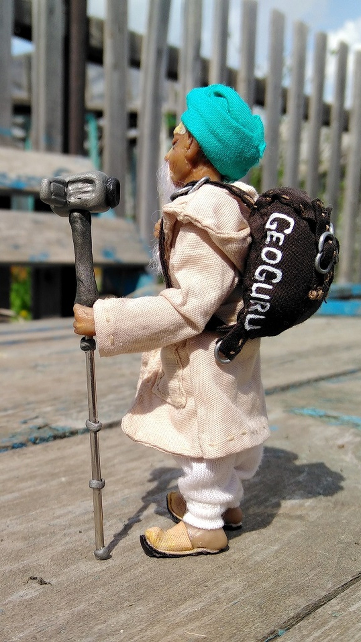 Traveler mascot doll with a brand backpack, turquoise turban and camera pole, made to order for a travel brand