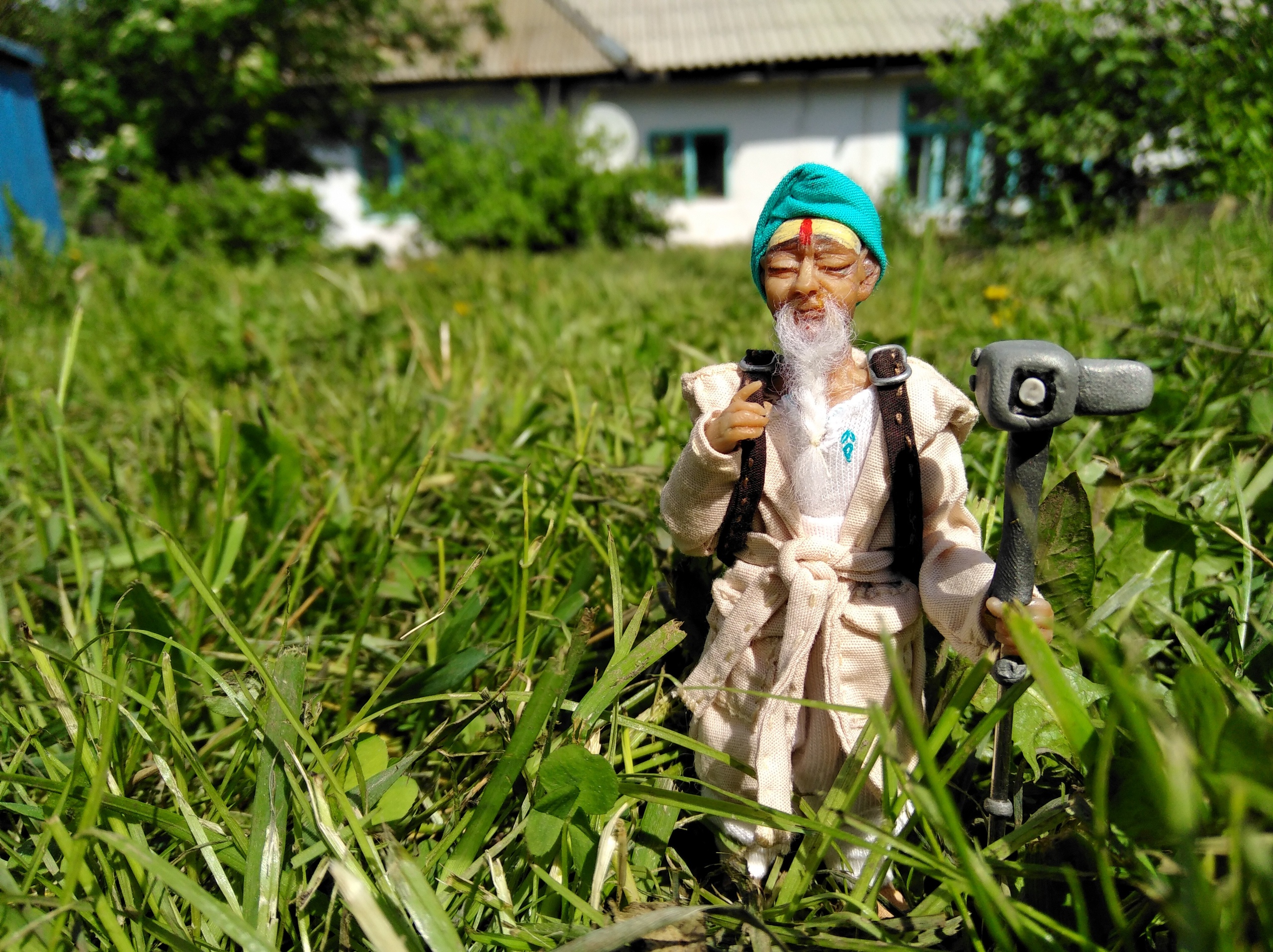 Custom traveler mascot doll outdoors Polymer clay traveler doll in a turban and cream coat in tall grass, a custom brand mascot made to order