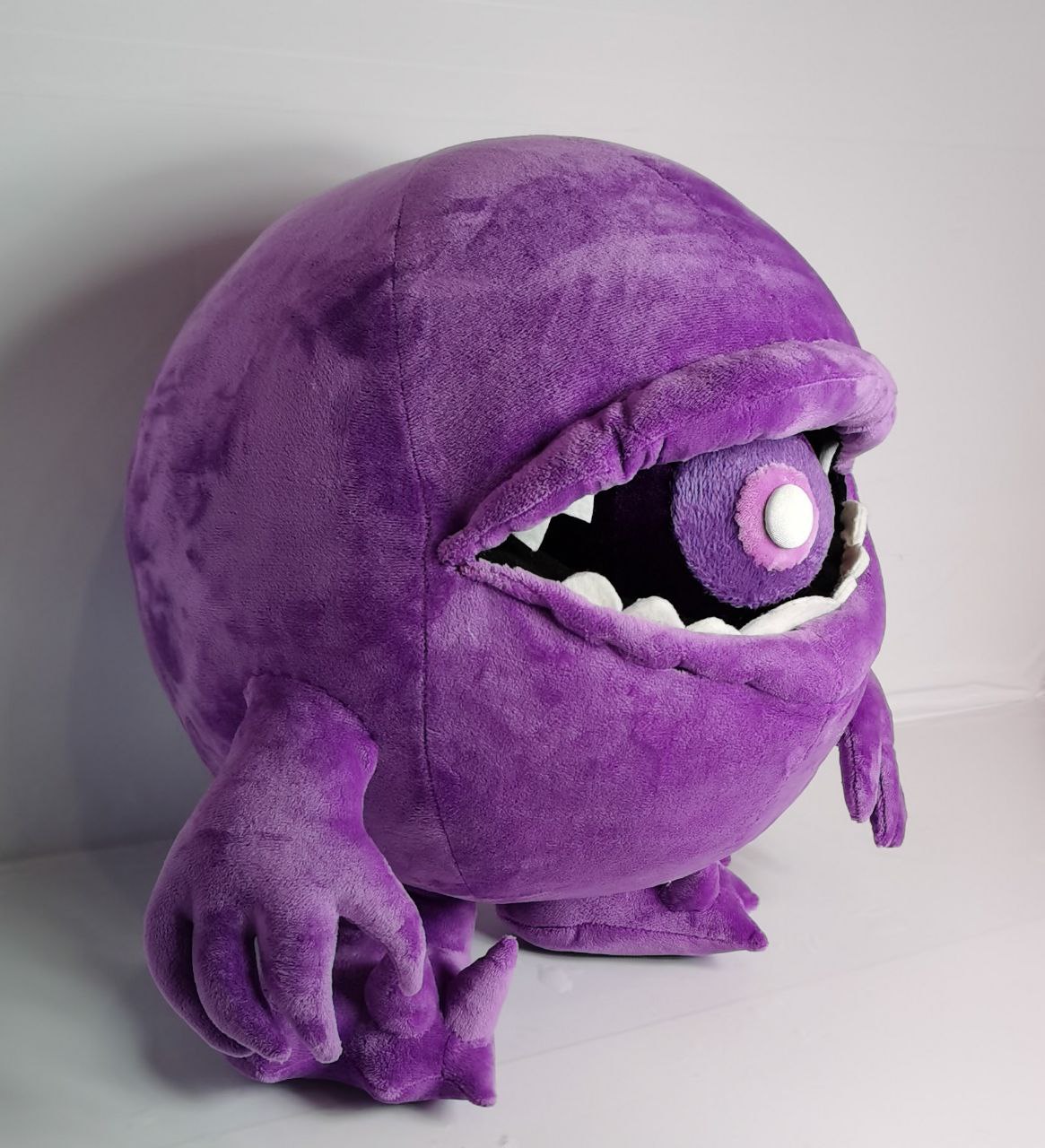 Custom monster plush with clawed arms Custom monster plush in soft purple plush with clawed arms, spiky feet and a ball in its toothy mouth