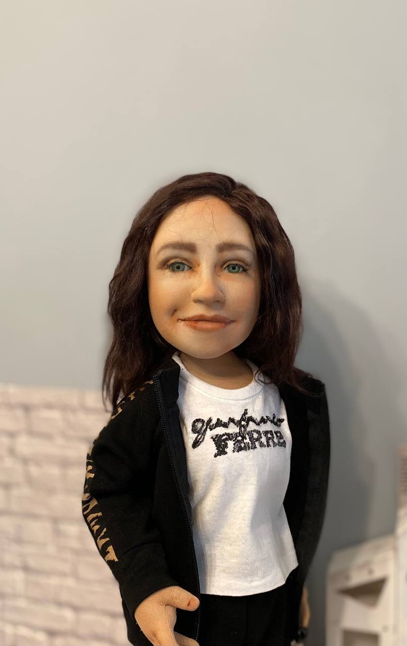 Hand-painted face of a portrait doll Custom portrait doll with a hand-painted face: green eyes, soft smile, dark wavy hair, white T-shirt