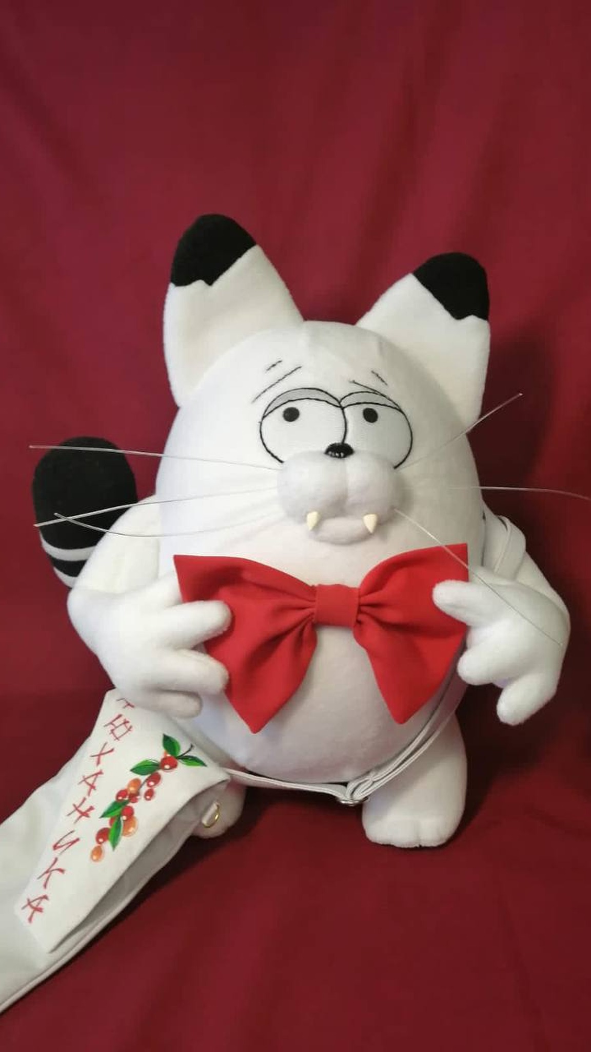 Custom white cat plush Kokos with his painted berry shoulder bag and red bow tie, made to order