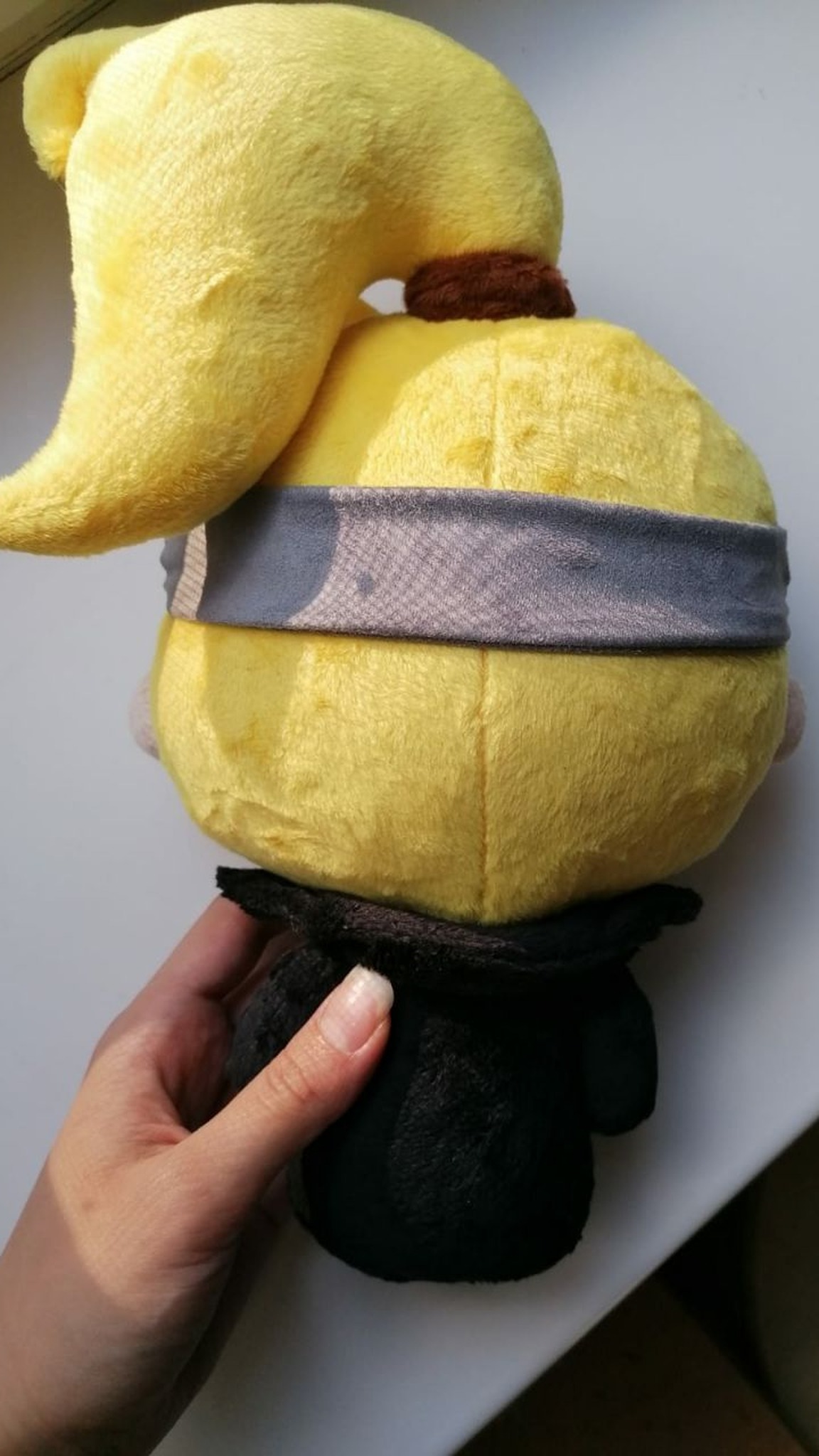 Back of a handmade Deidara plush: blond ponytail, brown hair tie and grey Naruto headband, sewn to order