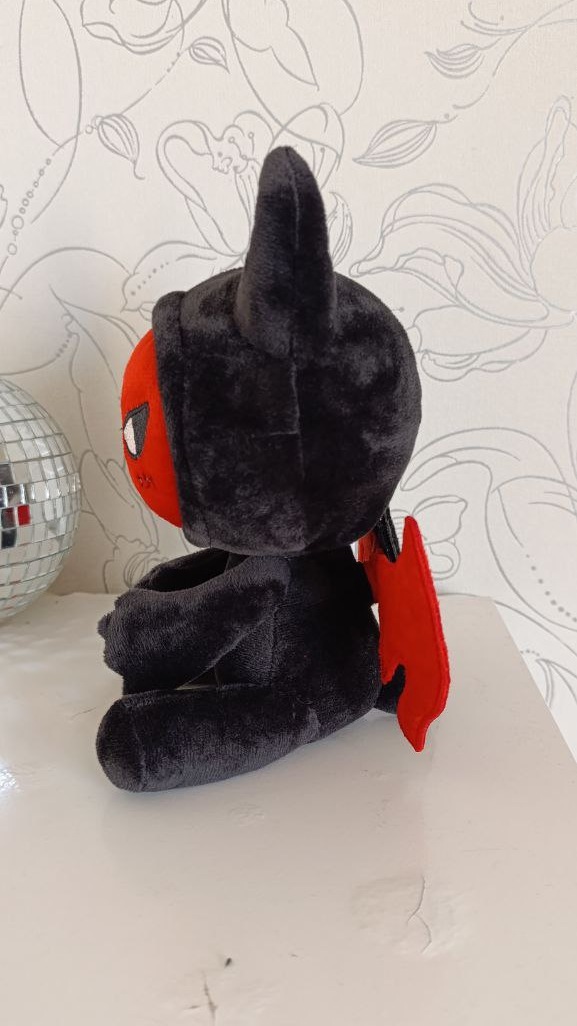 Custom devil plush mascot in profile: black hood with soft horns, red face and red wing, sewn by hand to order