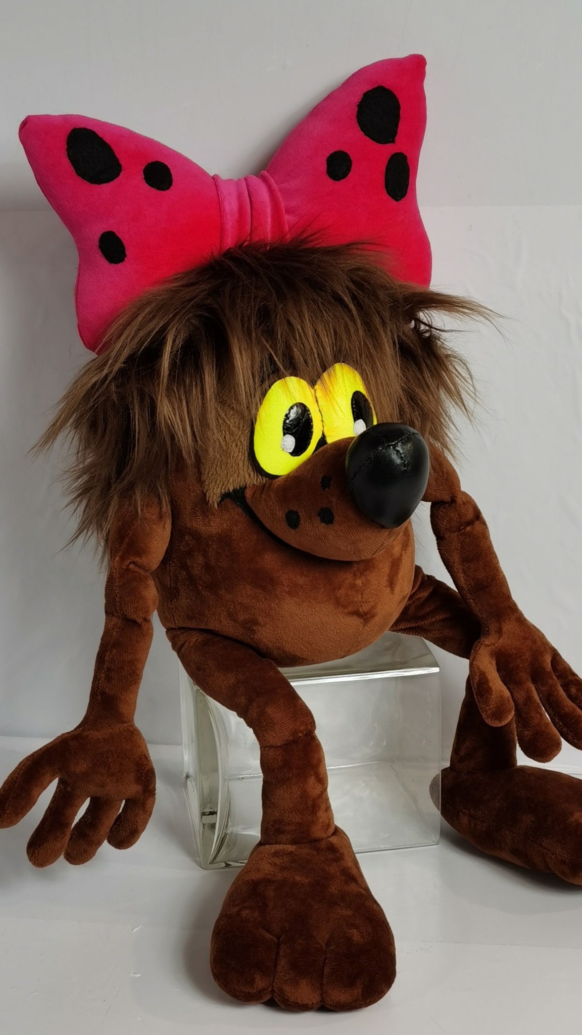 Dyudyuka plush sewn to order, sitting with legs hanging: sly grin, freckled muzzle, pink bow with black spots