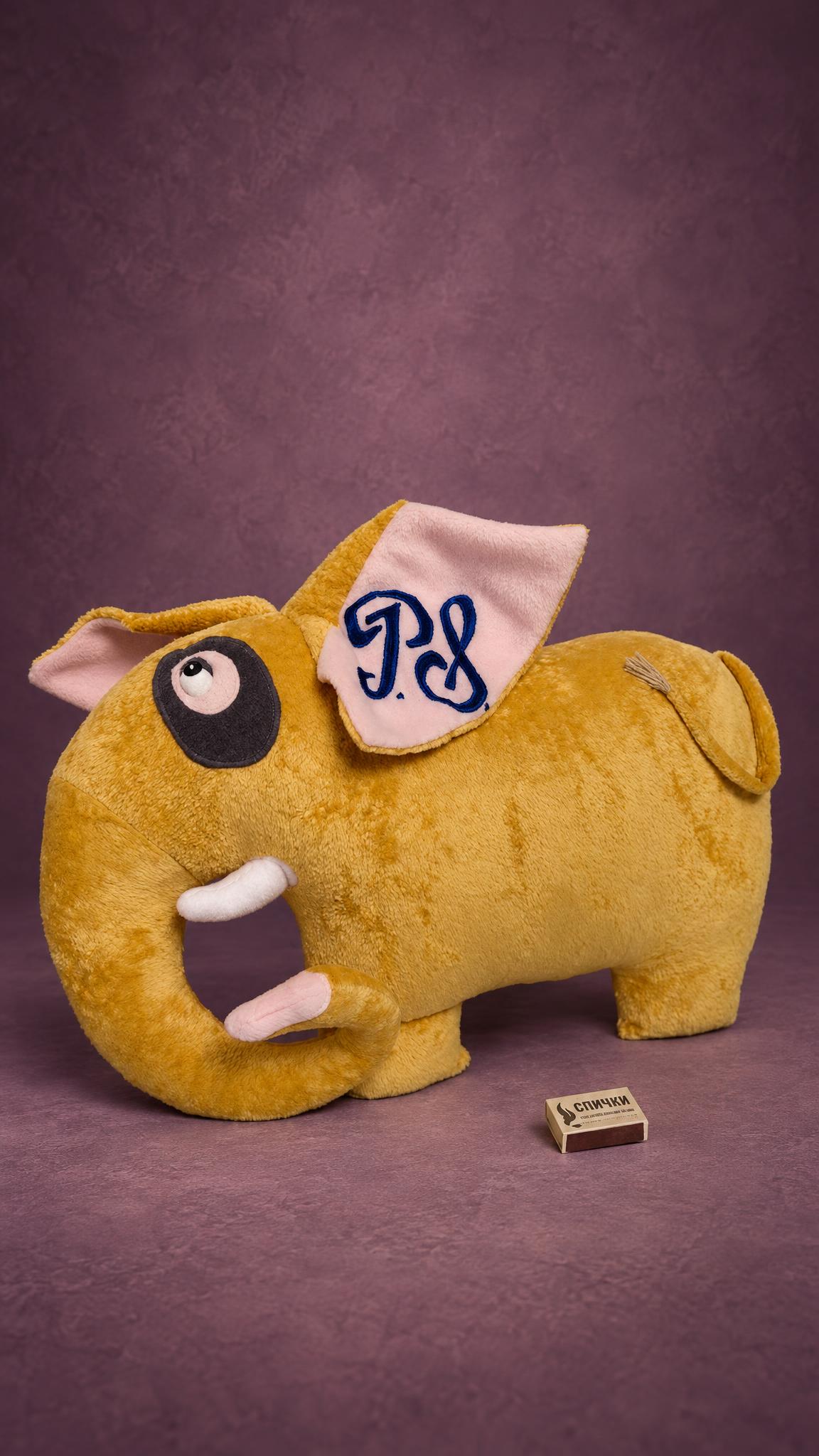 Custom elephant pillow plush with a logo on the ear, curled trunk and upward eye, handmade corporate gift