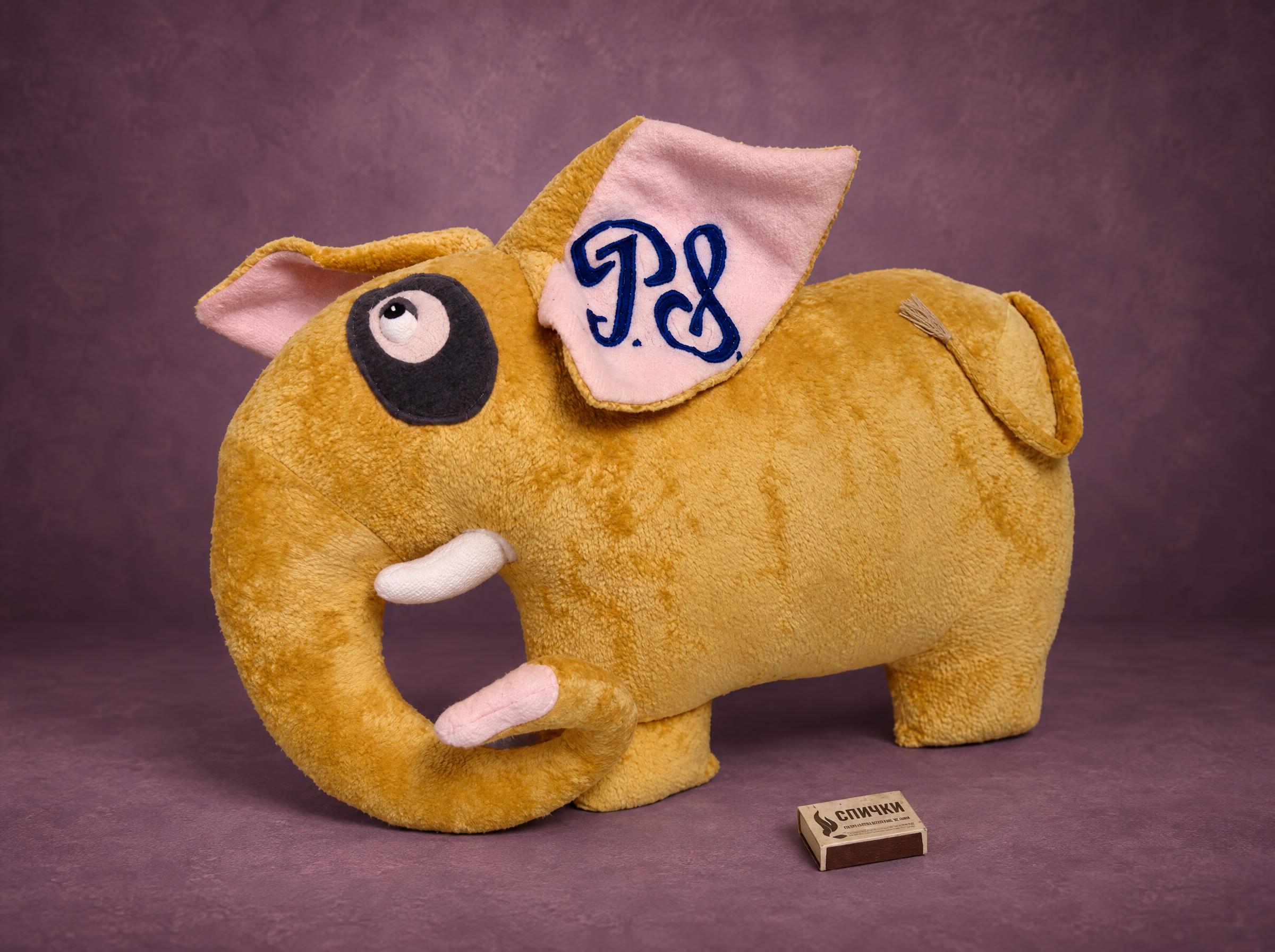 Elephant pillow plush in mustard yellow with a company monogram embroidered on its pink ear, made to order
