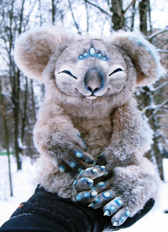 Koala plush with turquoise spots in the snow Custom koala plush with turquoise spots on long grey fingers, held in a gloved hand in the snow