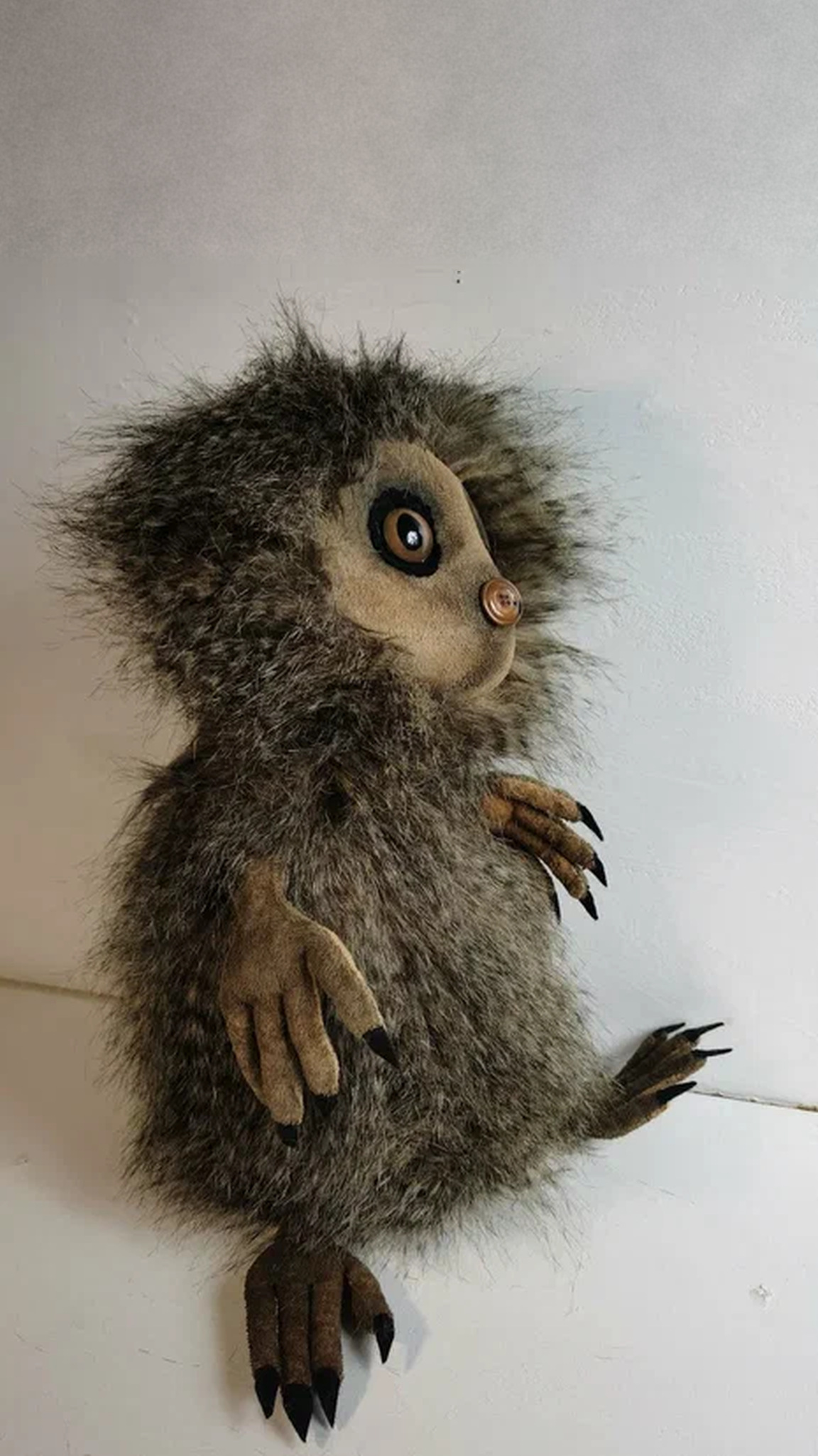 Shaggy forest creature plush with a button nose, long fingers and black claws, a custom plush from a drawing