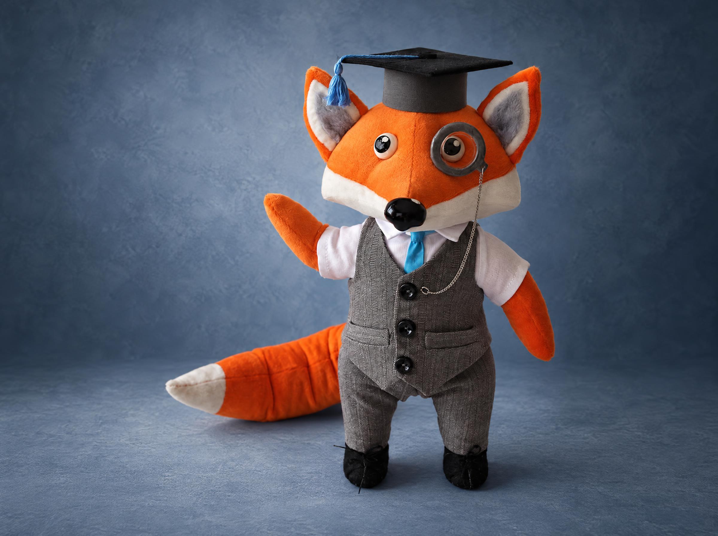 Fox mascot plush in a herringbone vest, blue tie, monocle and graduation cap, handmade to order for a company