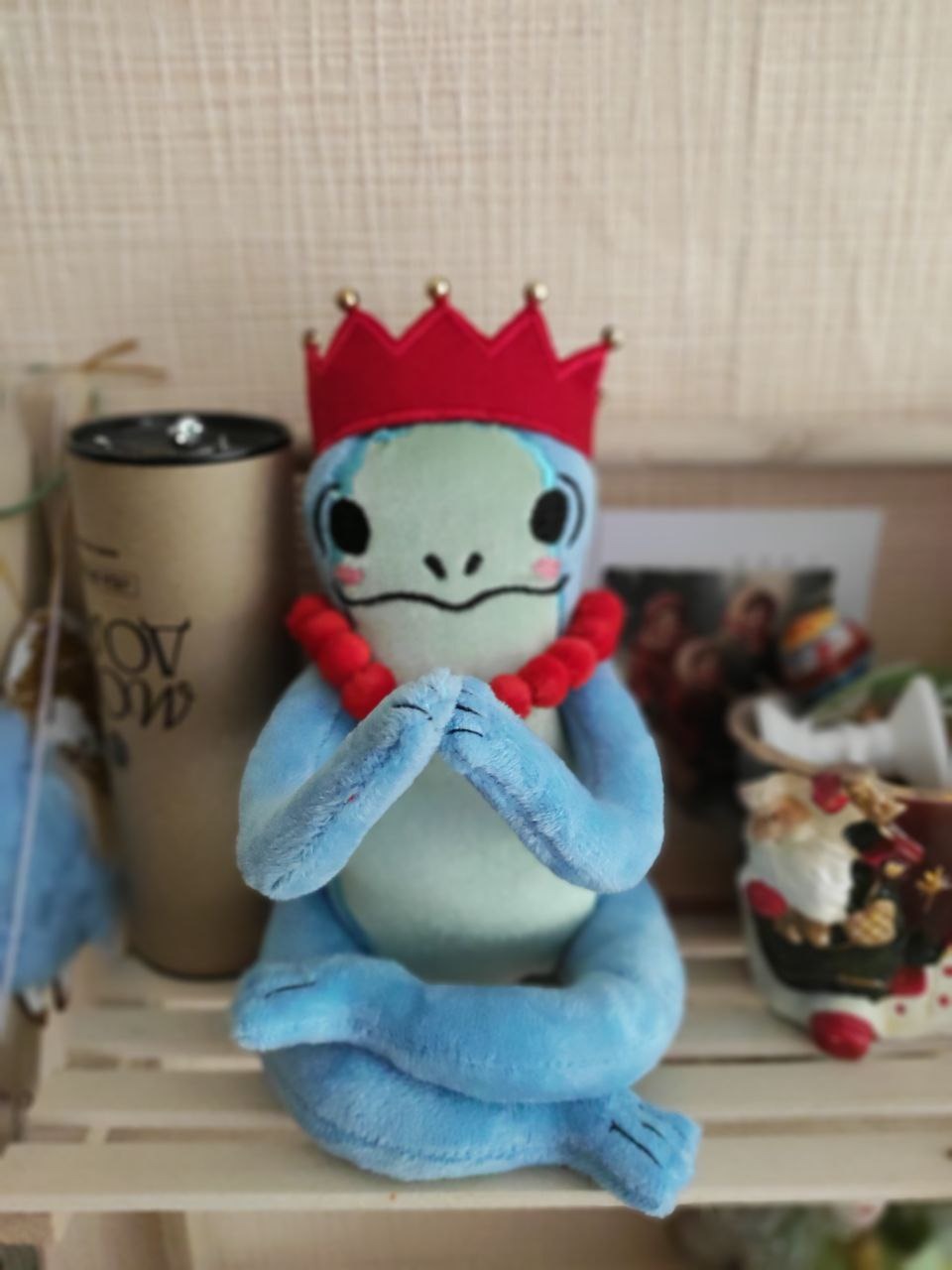 Frog plush with crossed legs Frog plush with crossed legs and hands pressed together, red crown, handmade frog princess from a sticker
