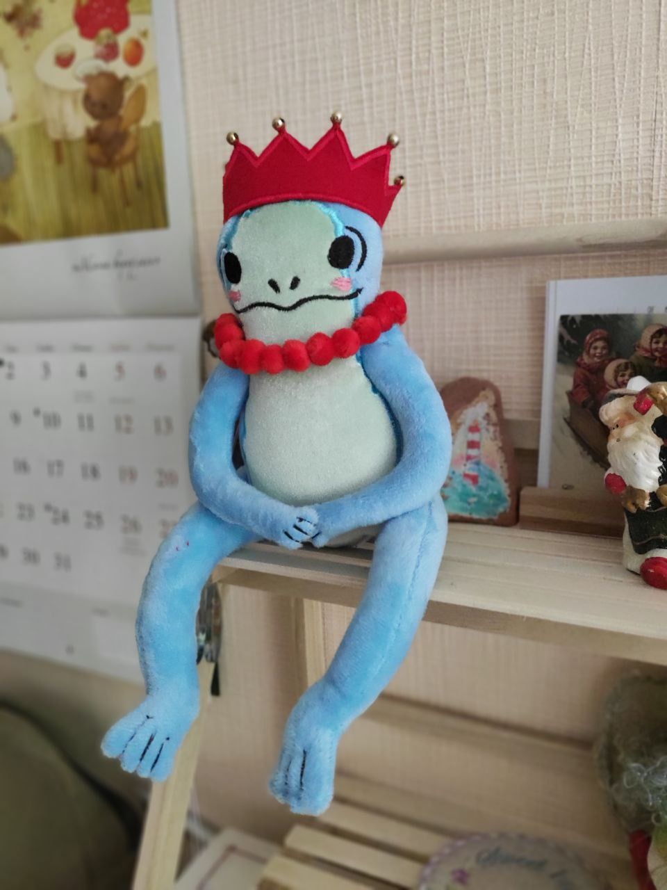 Frog princess plush on a shelf Frog princess plush sitting on a shelf edge, hands folded, red crown and pom-pom necklace, made to order