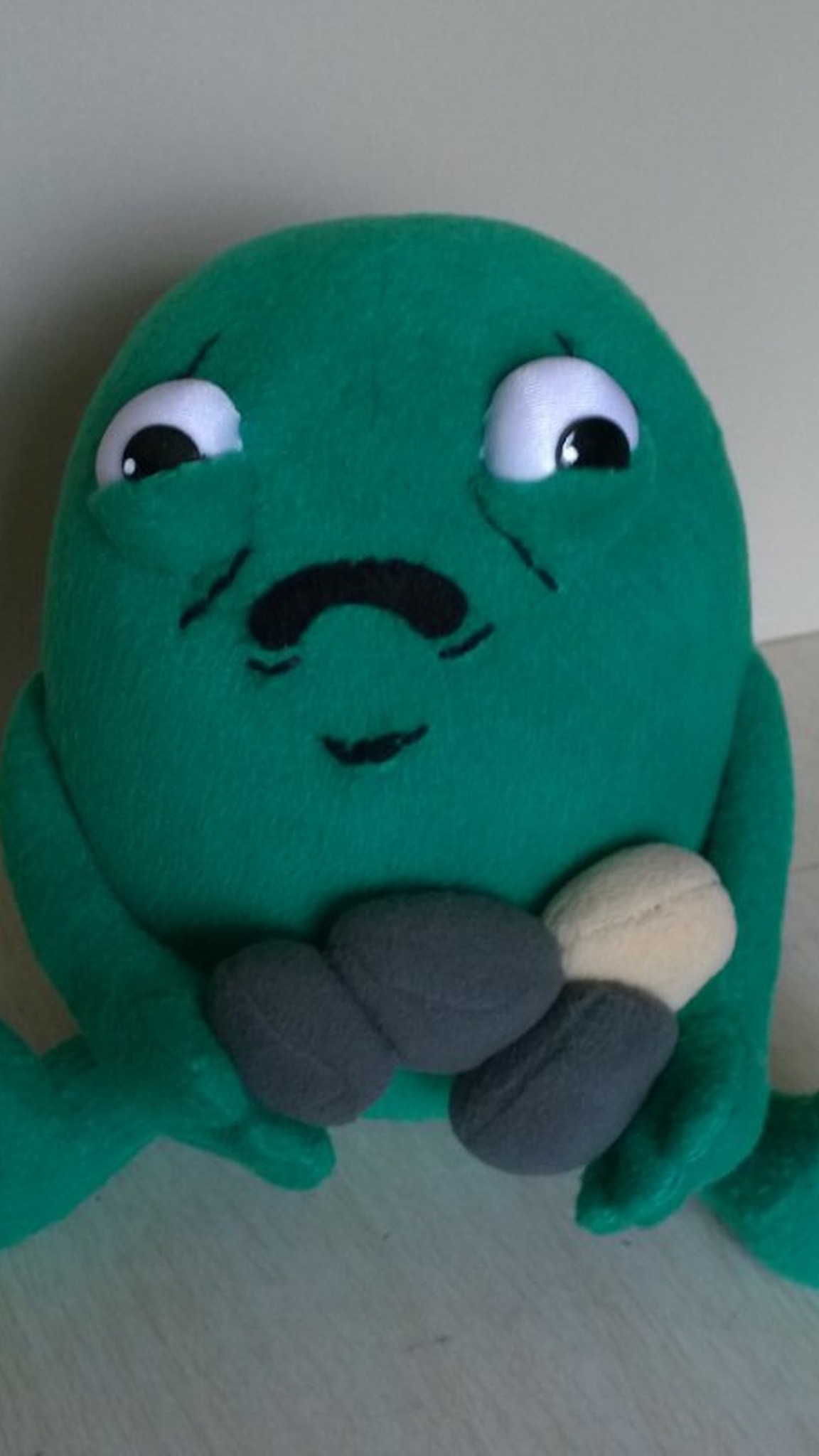 Gallbladder meme plush sitting with four plush stones, green soft body and stubby legs, custom made to order