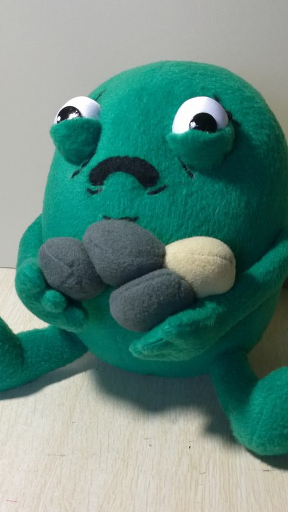 Custom gallbladder plush clutching his gallstones, sad white eyes and stitched frown, sewn by hand to order