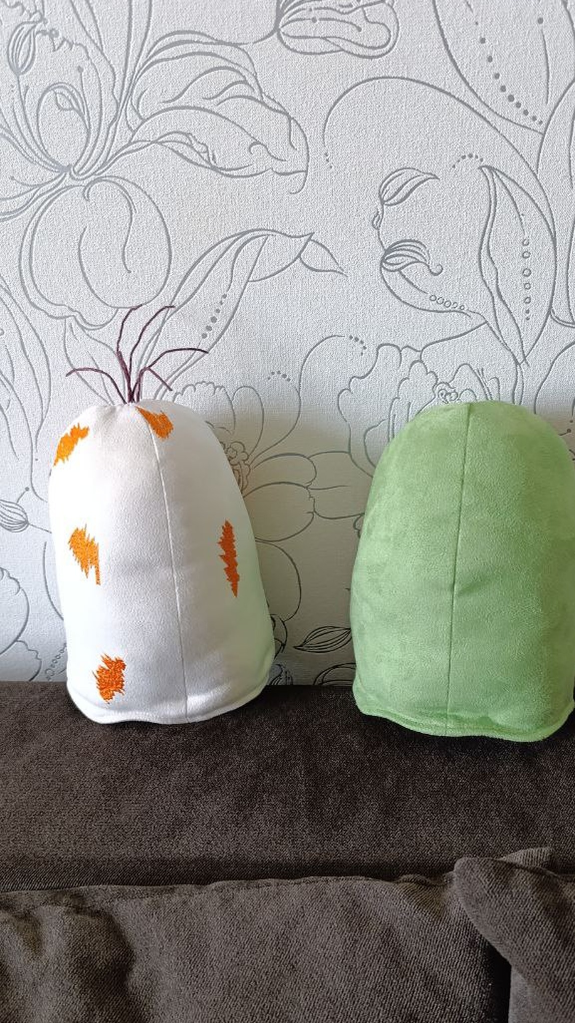 Custom ghost plushies from behind, white with embroidered orange marks and plain green, made to order