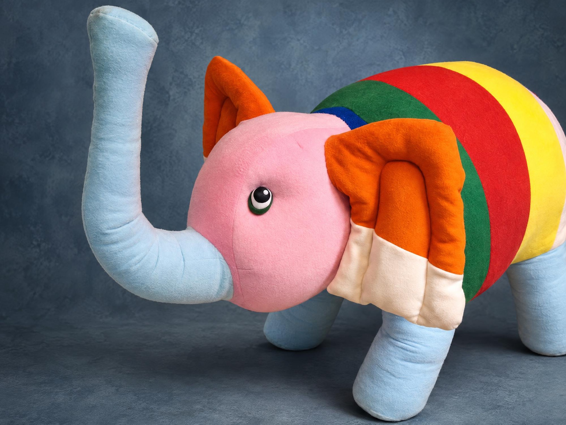 Giant elephant plush sewn to order from a kid's crayon drawing: pink head, blue trunk, rainbow-striped body