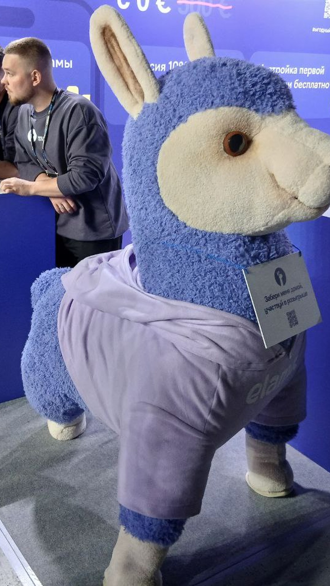 Giant llama plush mascot at a trade show booth, as tall as the visitors, sewn to order in brand colors