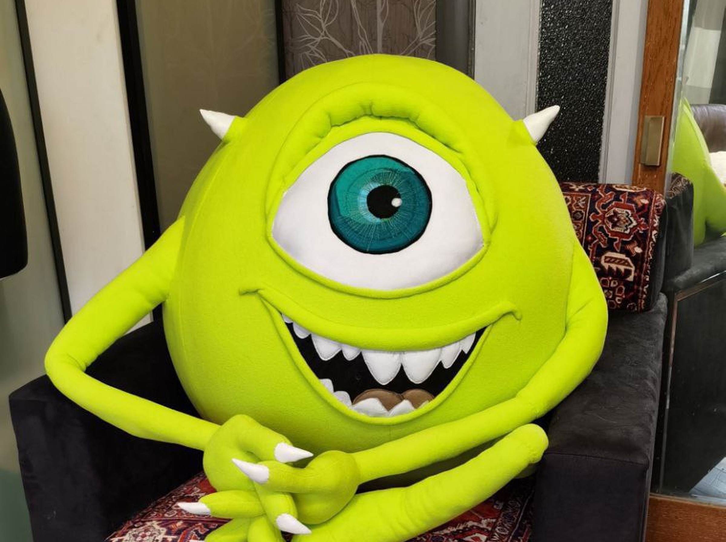 Giant Mike Wazowski plush on a black armchair, lime green with a teal eye and white teeth, made to order