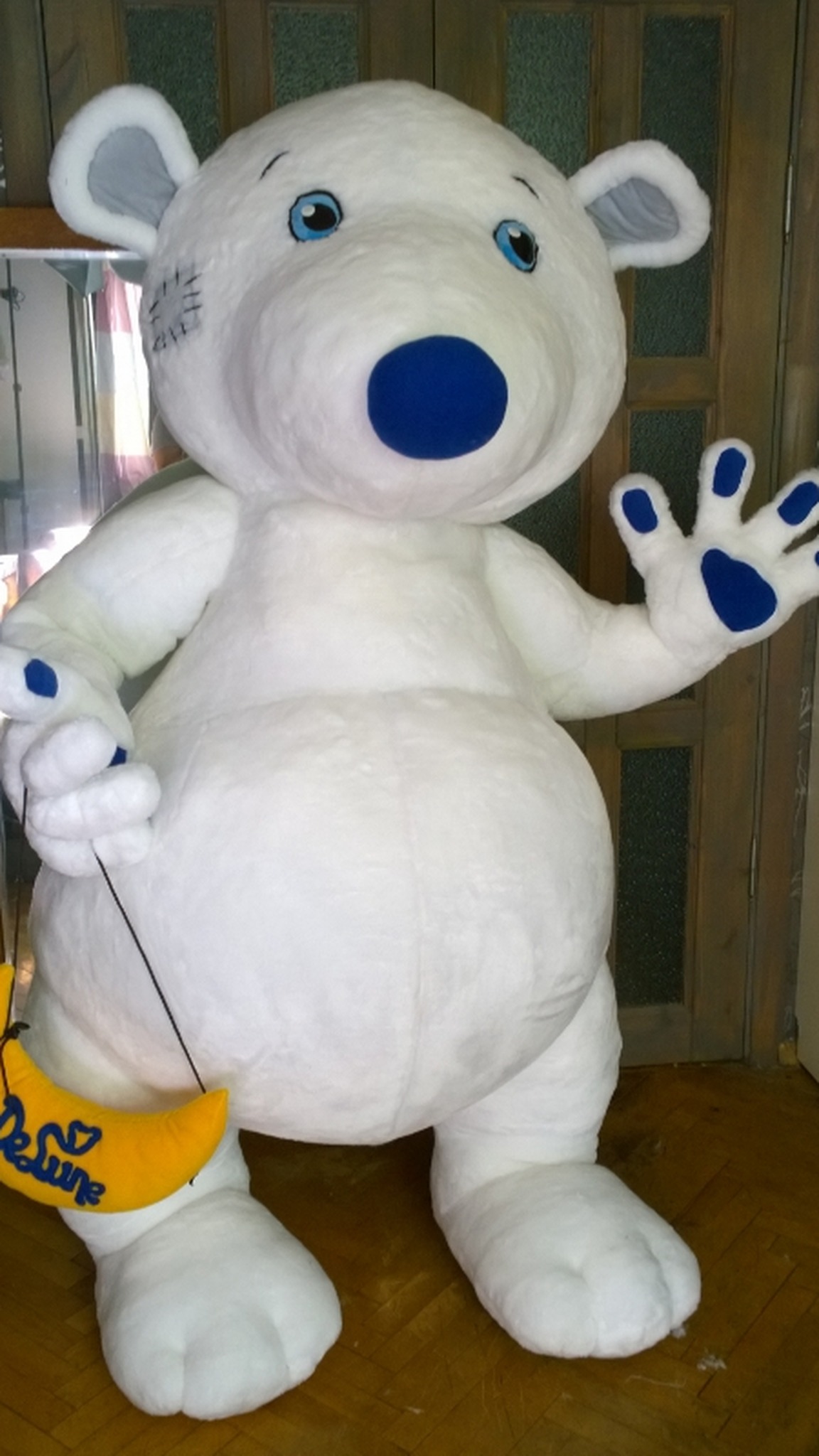 Giant white bear mascot plush with blue eyes and a stitched forehead patch, custom made from brand art