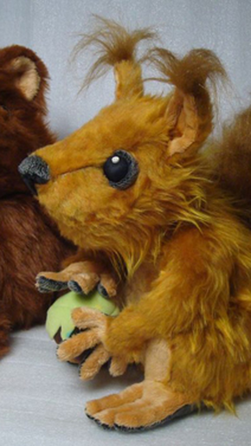 Ginger squirrel plush with ear tufts holding a green hazelnut, custom made from a Skype emoticon