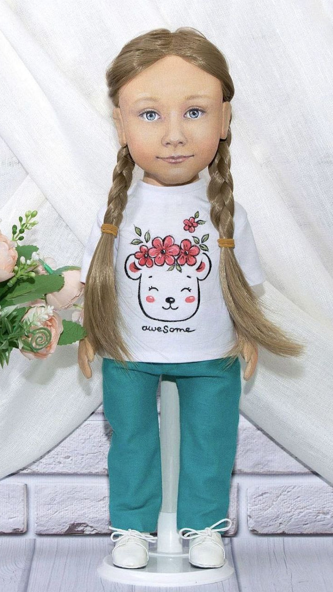 Girl portrait doll with two braids in a bear-print "awesome" T-shirt and teal pants, second outfit sewn to order