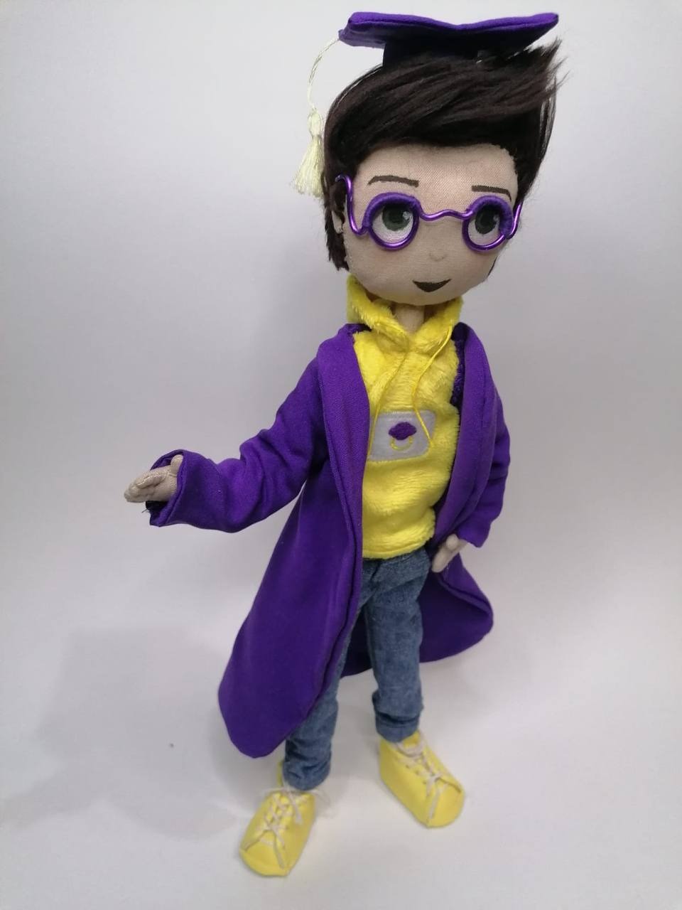 Graduate mascot doll with a tasseled cap Handmade graduate mascot doll holding out one hand, cream tassel on his violet cap, sewn to order