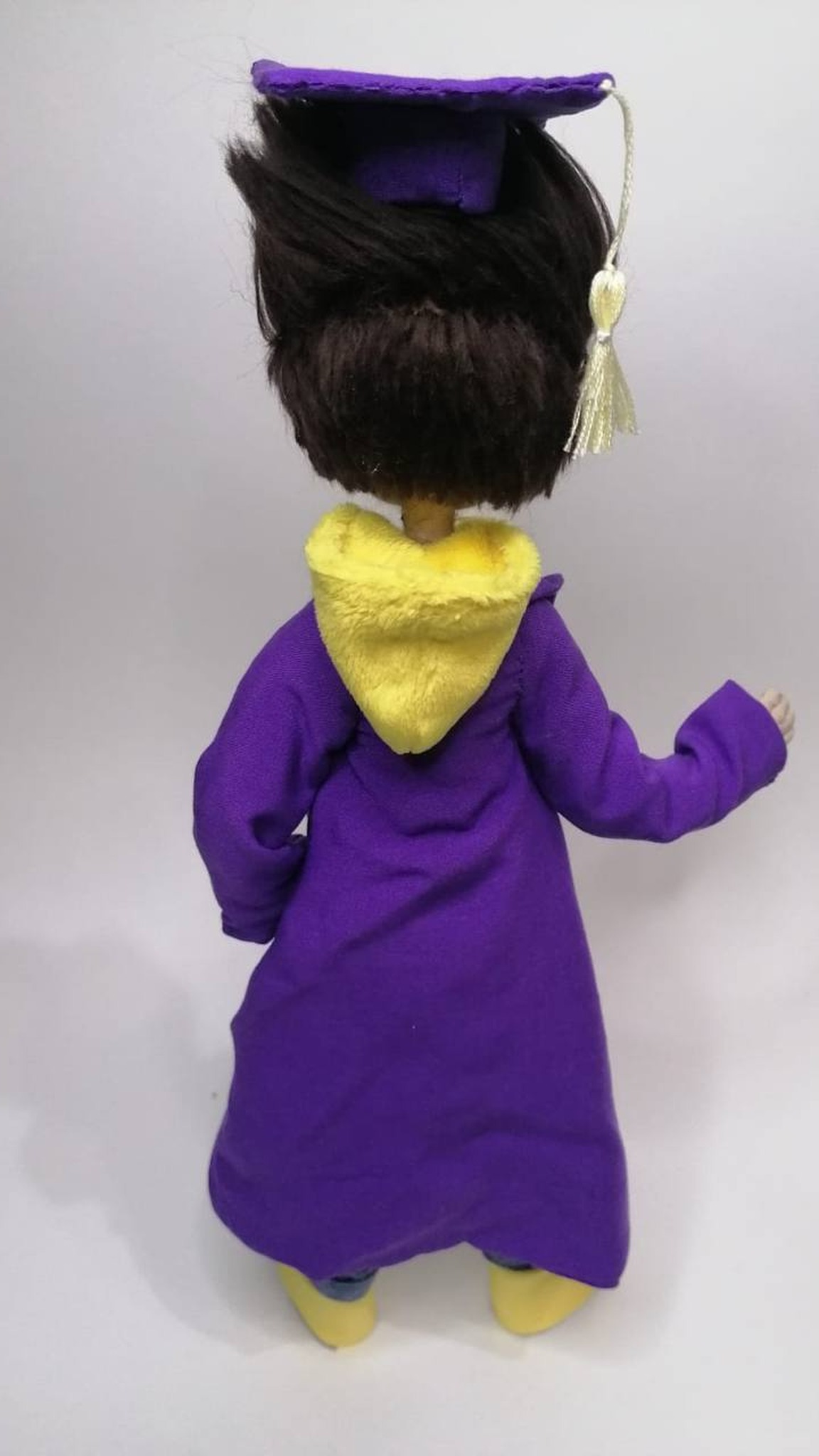 Violet gown with a yellow plush hood on the handmade graduate mascot doll, sewn to order