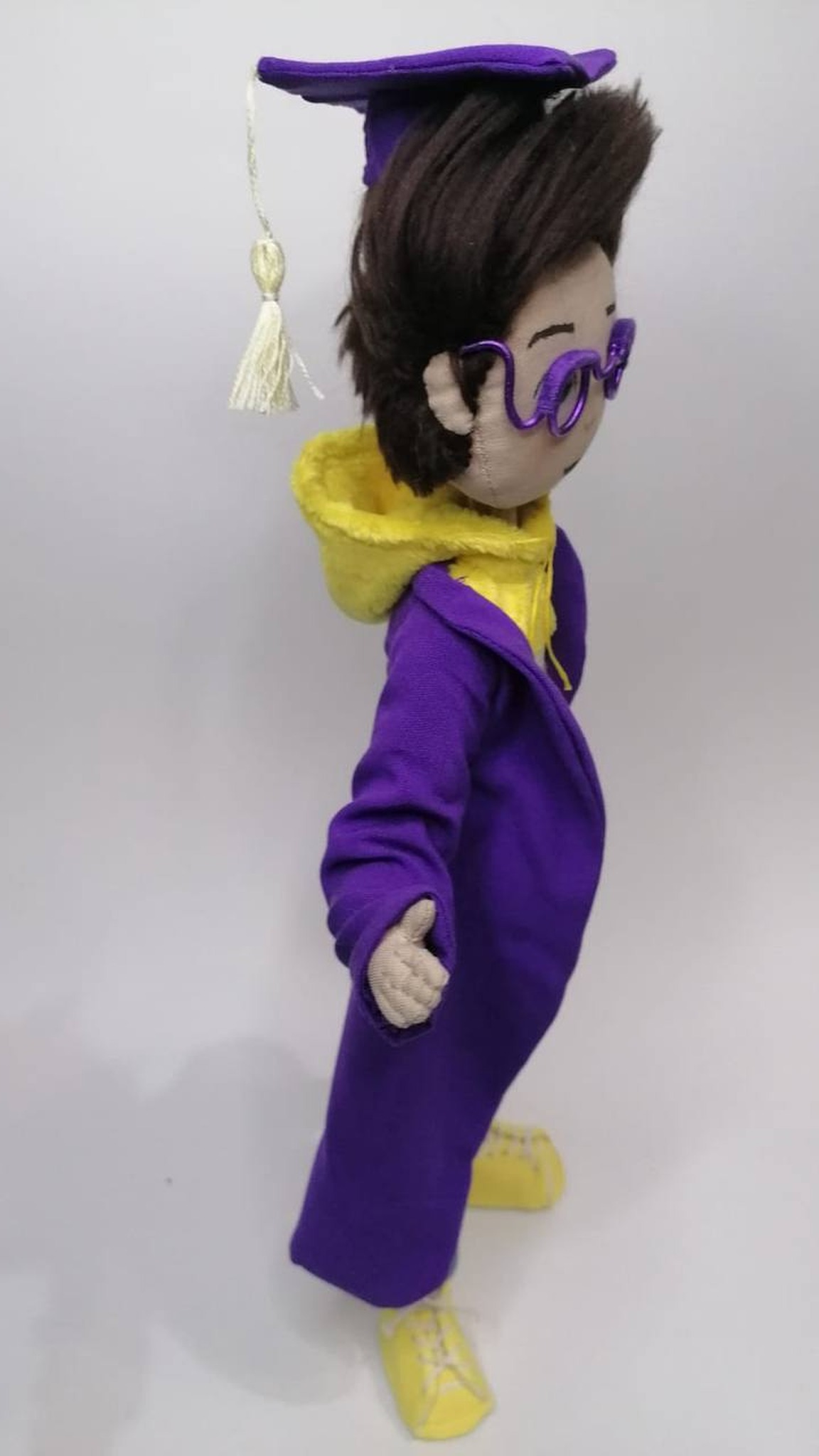 Custom graduation doll in a long violet gown with wire glasses and a tasseled cap, made as a mascot