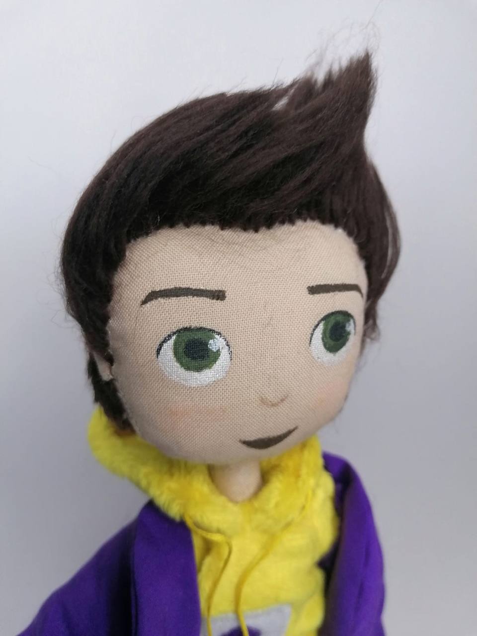 Mascot doll with a dark brown quiff Graduate mascot doll with painted green eyes, a dark brown quiff and a yellow hood, sewn by hand to order