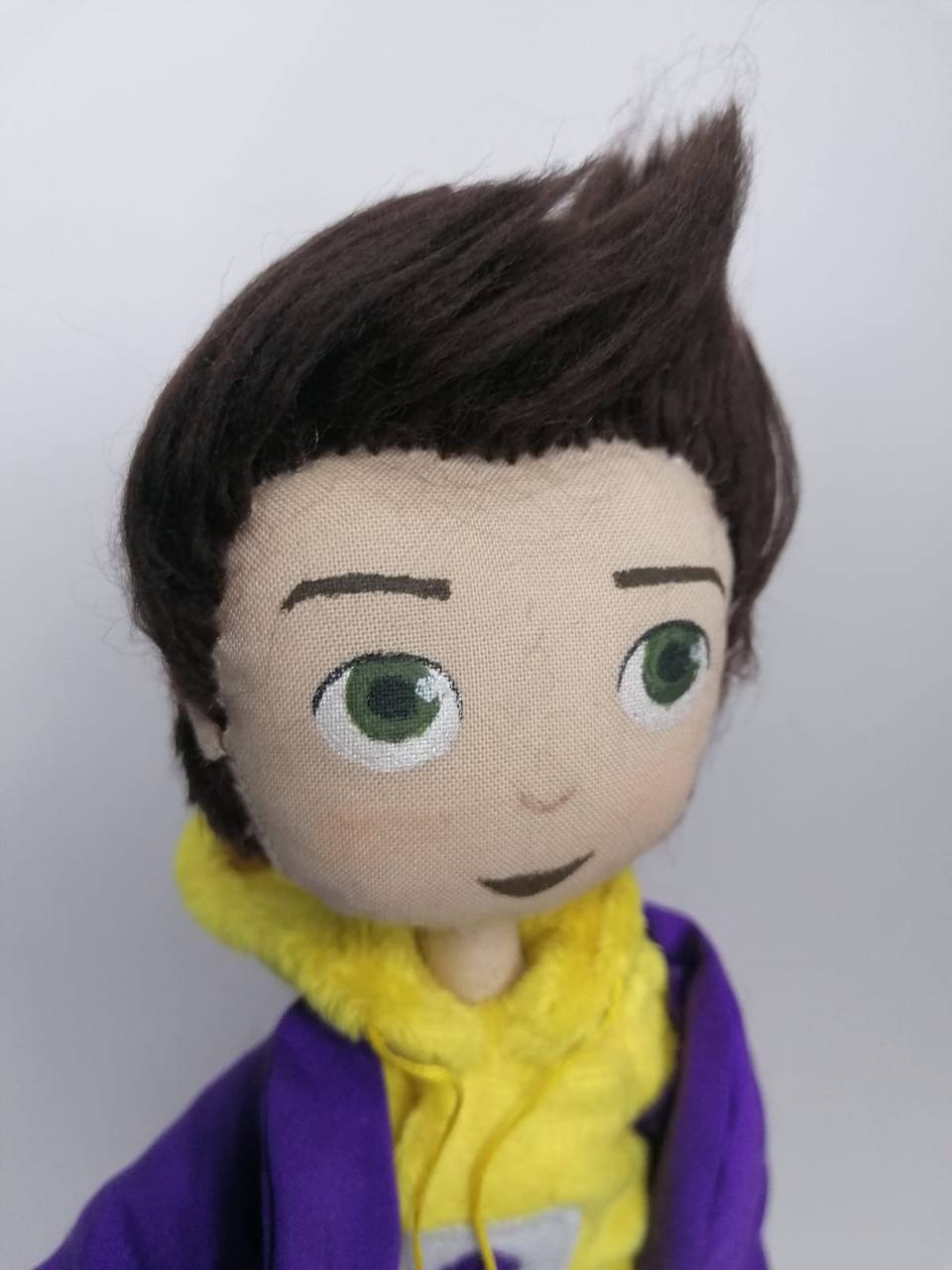 Painted face of the mascot doll Painted fabric face of the custom mascot doll: green eyes, brown brows, upswept quiff, handmade to order
