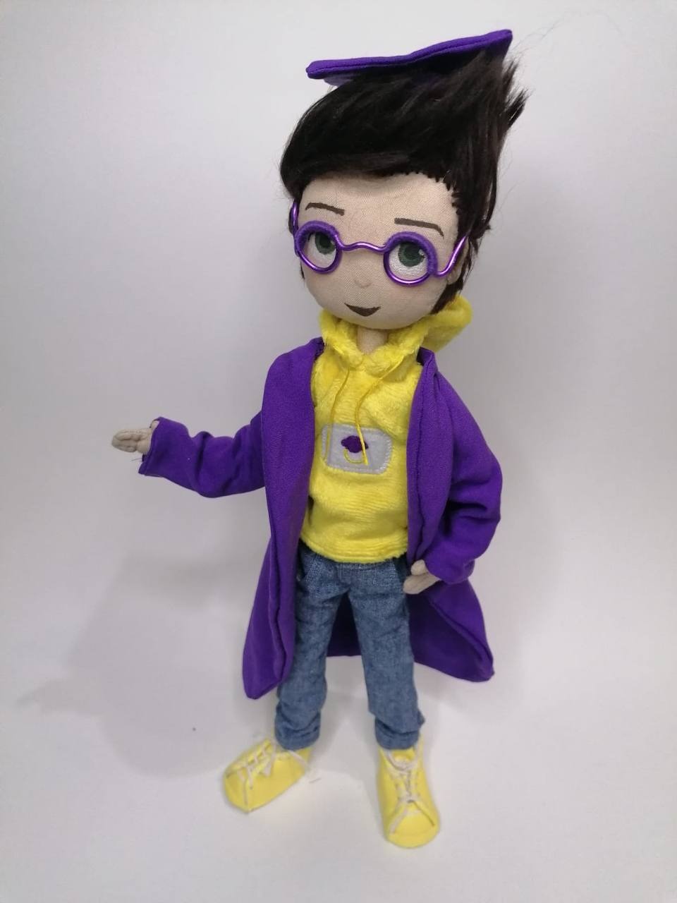 Graduate mascot doll presenting Handmade graduate mascot doll with one hand out as in the drawing, violet gown and yellow sneakers