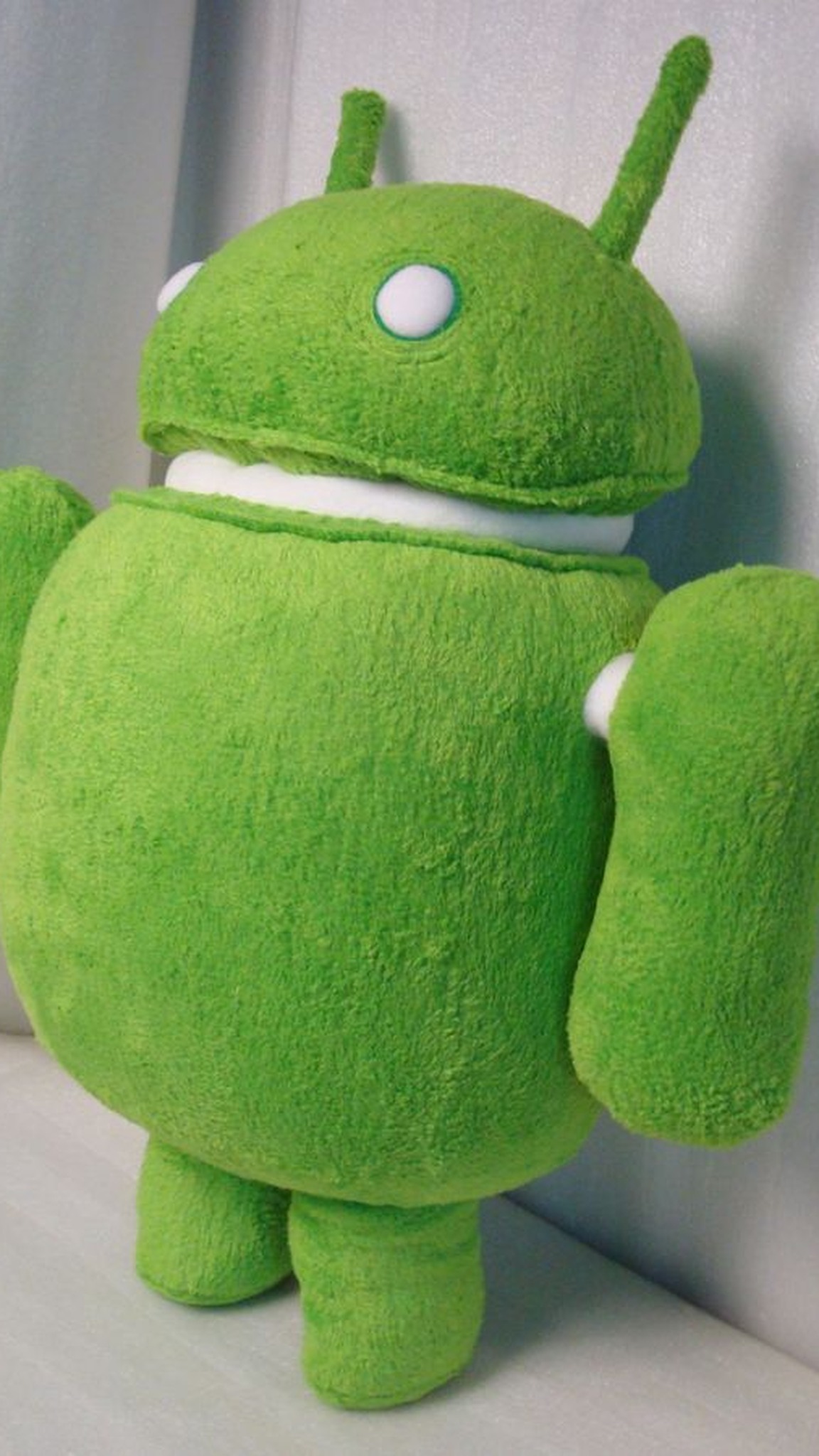 Green Android robot plush turned to the side, showing its round body, separate dome head and handmade arms
