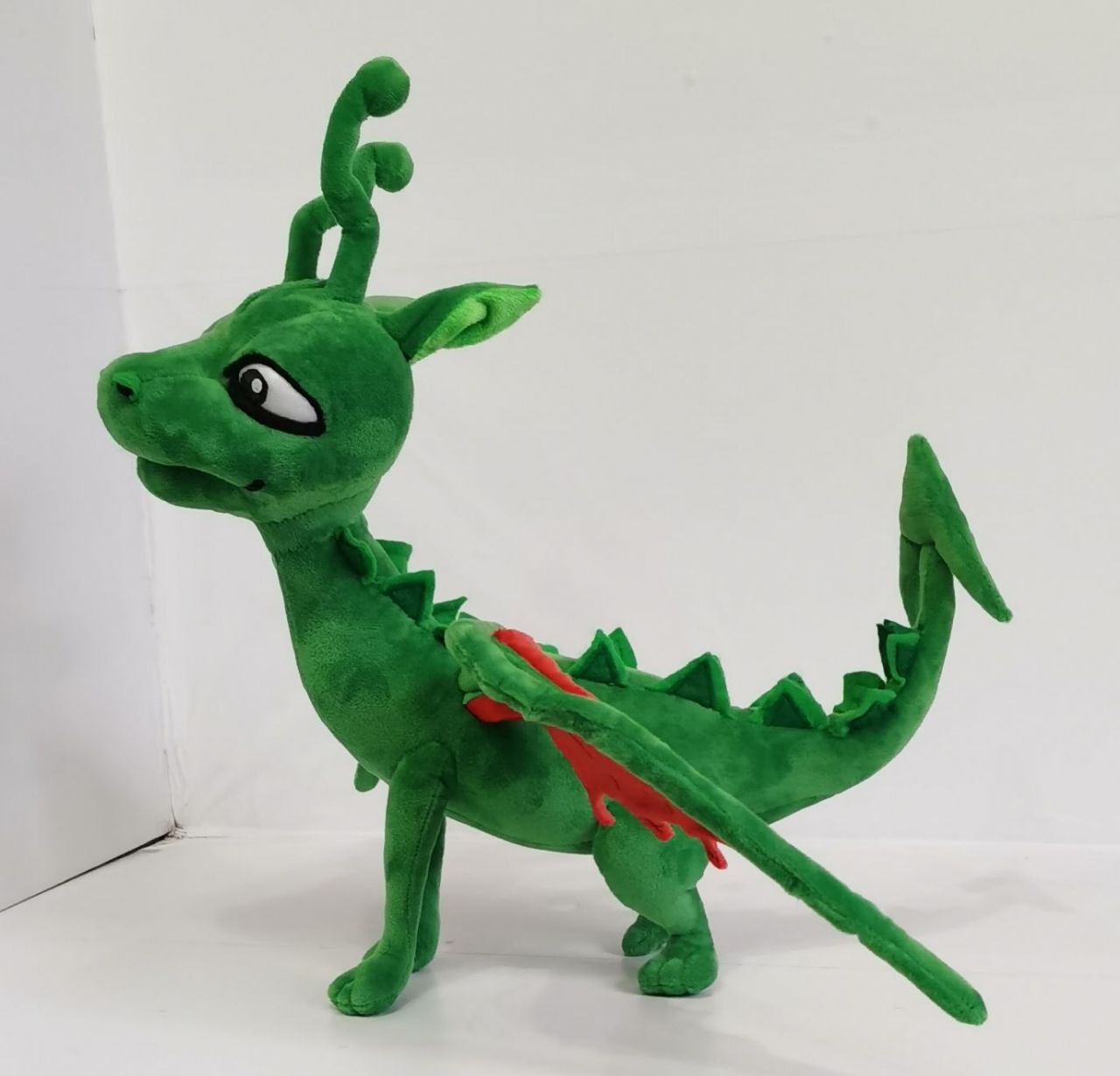 Green dragon plush with spiked tail Handmade green dragon plush with a long spiked tail and folded red-lined wing, a custom book dragon toy