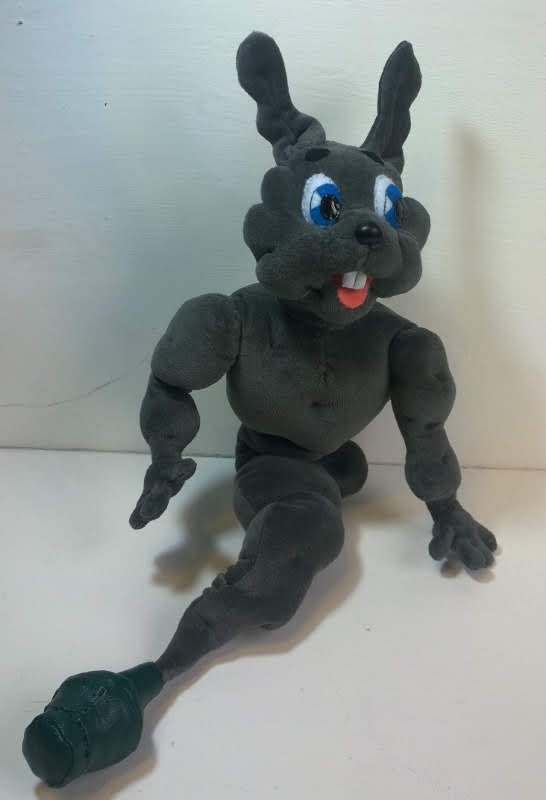 Grey bunny genie plush with a green bottle Grey bunny genie plush sitting up, long ears, blue felt eyes and a dark green bottle at the tail tip, made to order