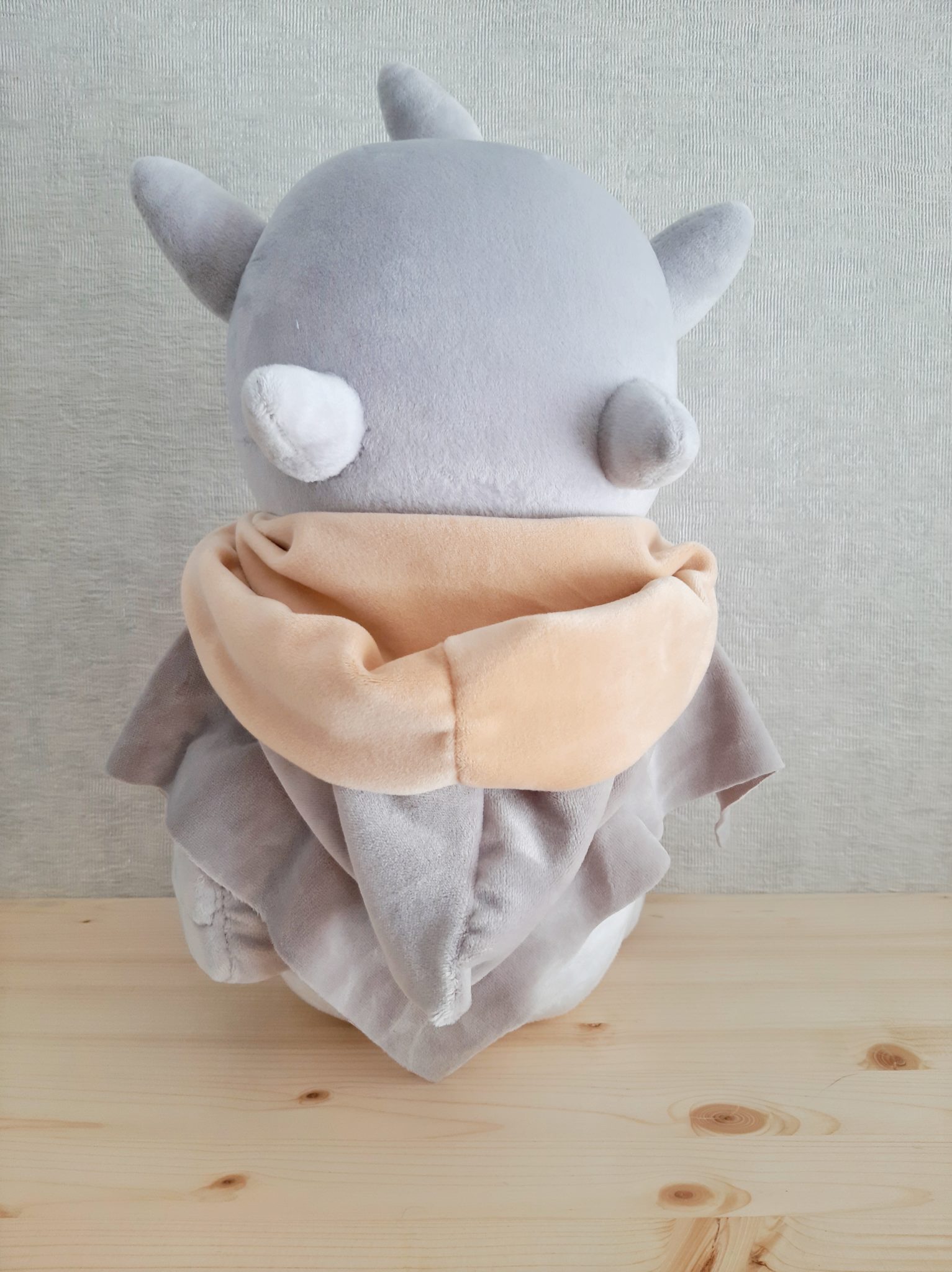 Grey monster plush with horns and a cloak Grey monster plush with horns and small nubs on its head, peach scarf and draped grey cloak, sewn to order