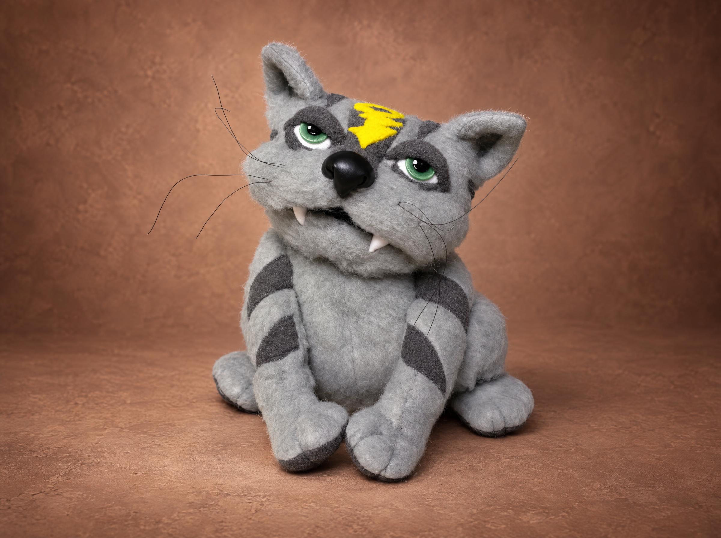Grey tabby cat plush with a yellow lightning bolt, green eyes and two fangs, handmade to order from a drawing
