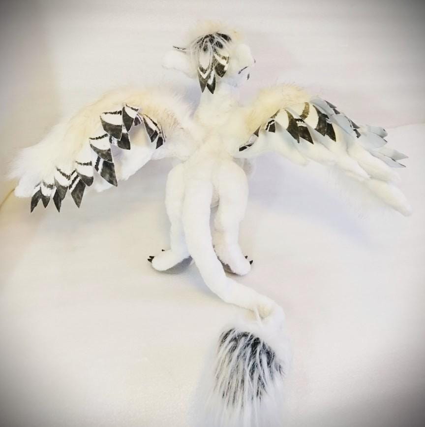 Griffin plush with wings spread Custom griffin plush with both wings spread wide and a tufted black-and-white tail, a gryphon sewn to order