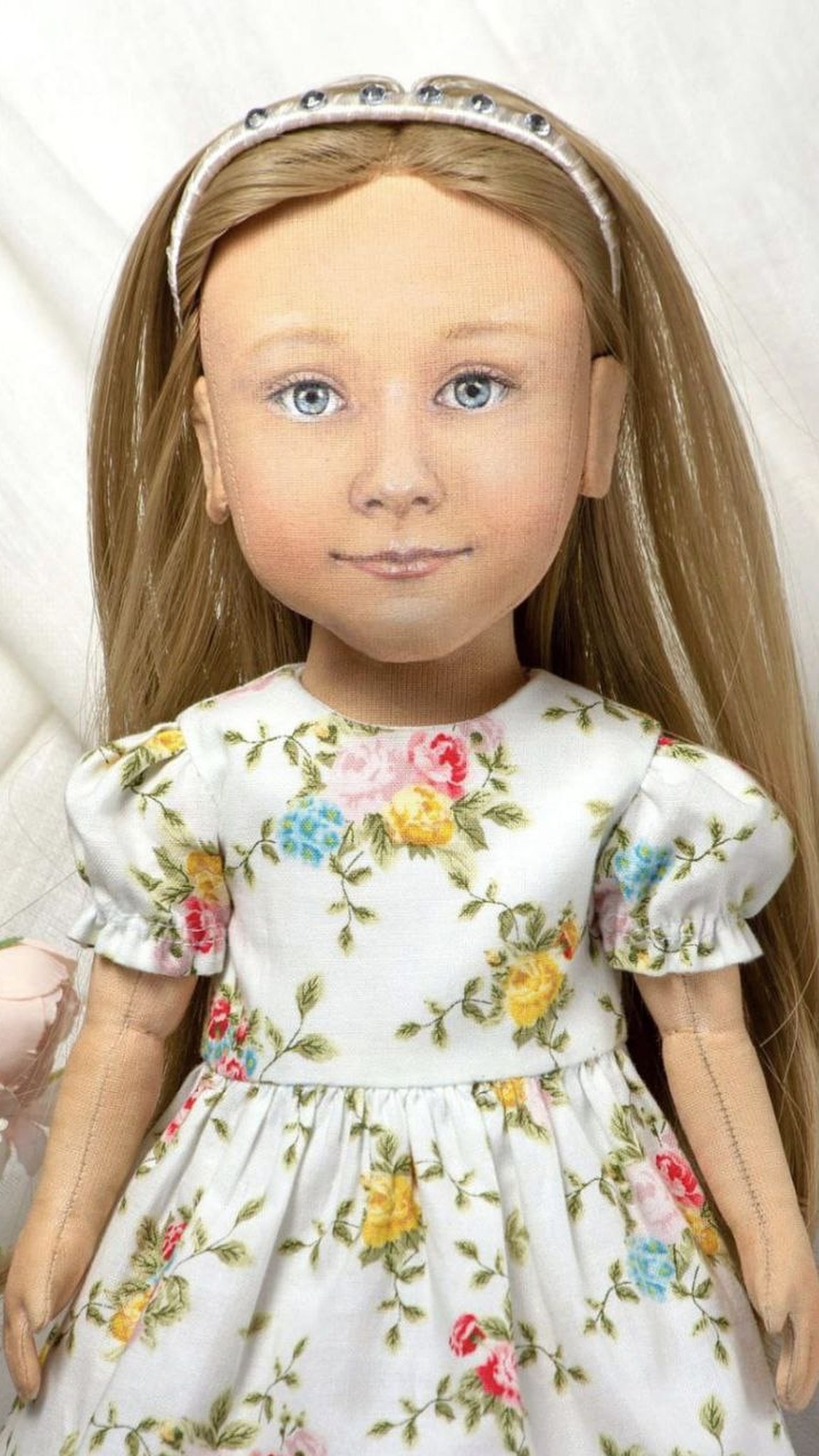 Hand-painted face of a custom girl portrait doll: blue eyes, soft smile, white headband, long dark-blonde hair