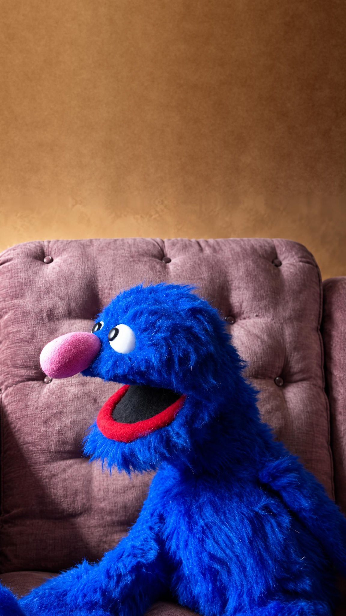 Handmade Grover plush sewn to order, shaggy bright blue fur, pink nose and red-lipped smile in a mauve armchair
