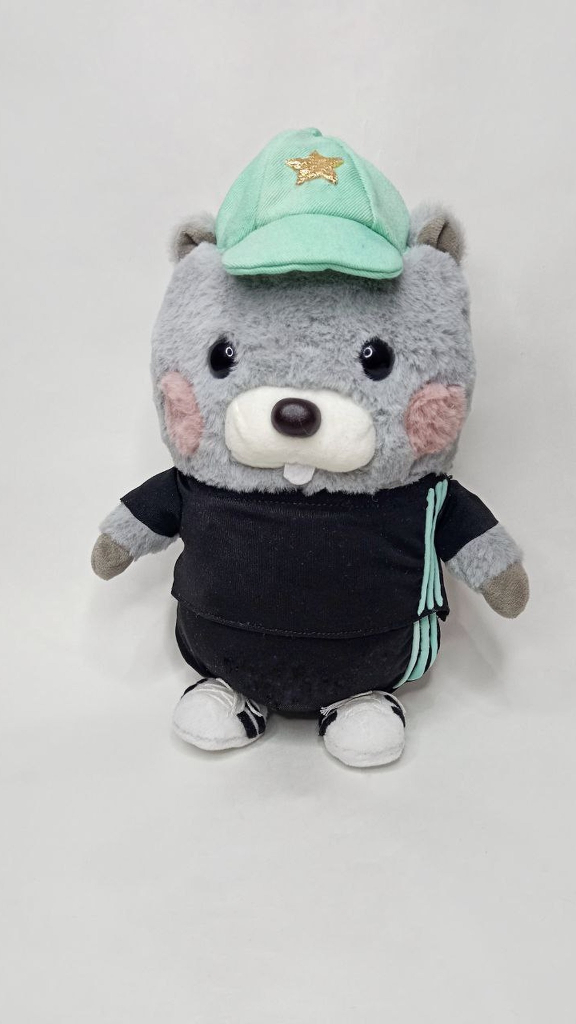 Handmade hamster plush sewn from a kid's drawing, standing in white sneakers with a gold star on his mint cap
