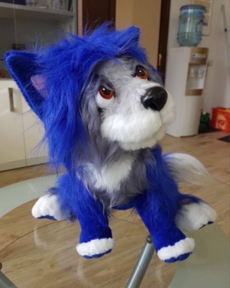 Wolfie plush sitting with one ear up Custom Wolfie plush from Vampirina sitting on a glass table, one blue ear up and paws forward, made by hand