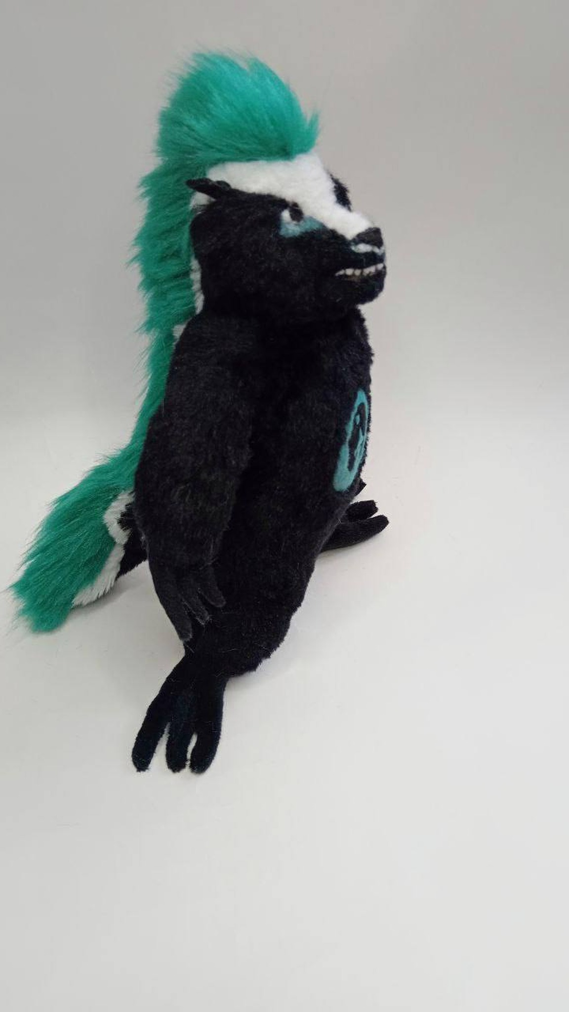 Honey badger mascot plush with a teal faux fur mohawk down its back, handmade to order for a company